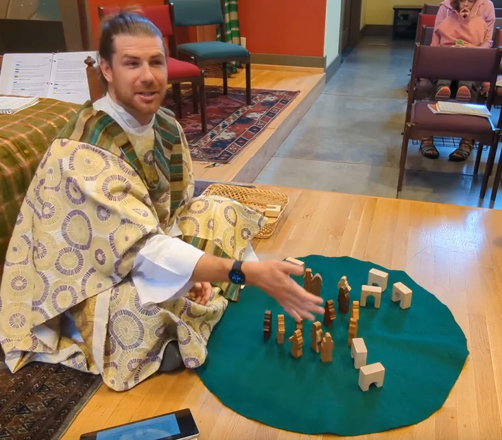 Peter arranging small wooden figures on a round green felt cloth